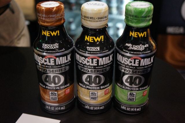 Three Muscle Milk Pro Series 40 protein shake bottles marked New: Knockout Chocolate, Intense Vanilla and Mint Chocolate Overload, on a dark table.