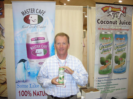 A man in a checked shirt holds a can of coconut juice between banners for Master Café iced coffee and Amy & Brian Coconut Juice.