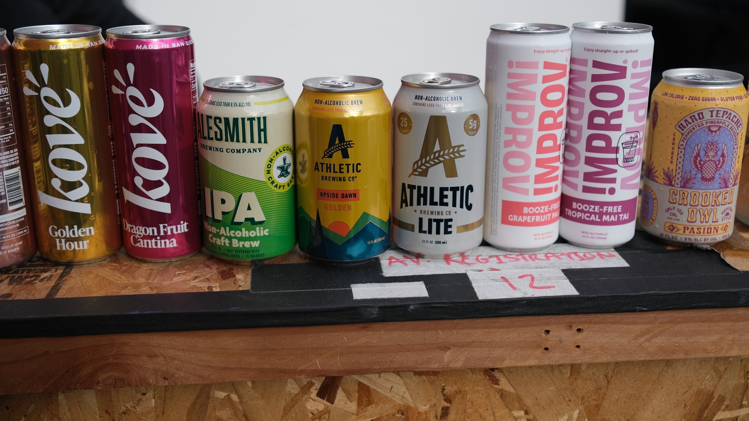 A row of cans including Kove, Athletic Brewing Lite and Improv on a wooden crate.