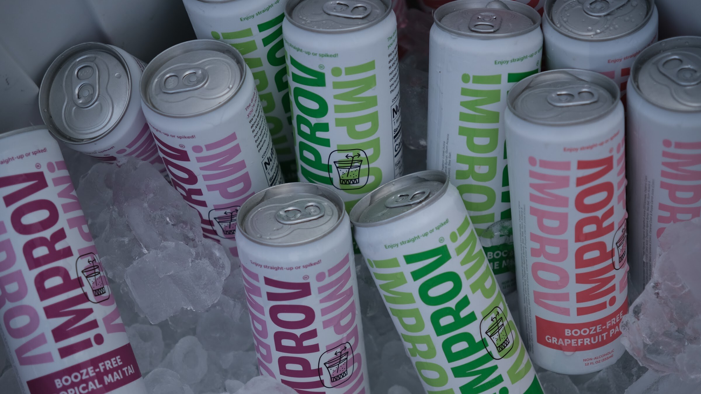 Pink, green and white Improv cans in lime margarita, tropical mai tai and grapefruit paloma flavors packed in ice.