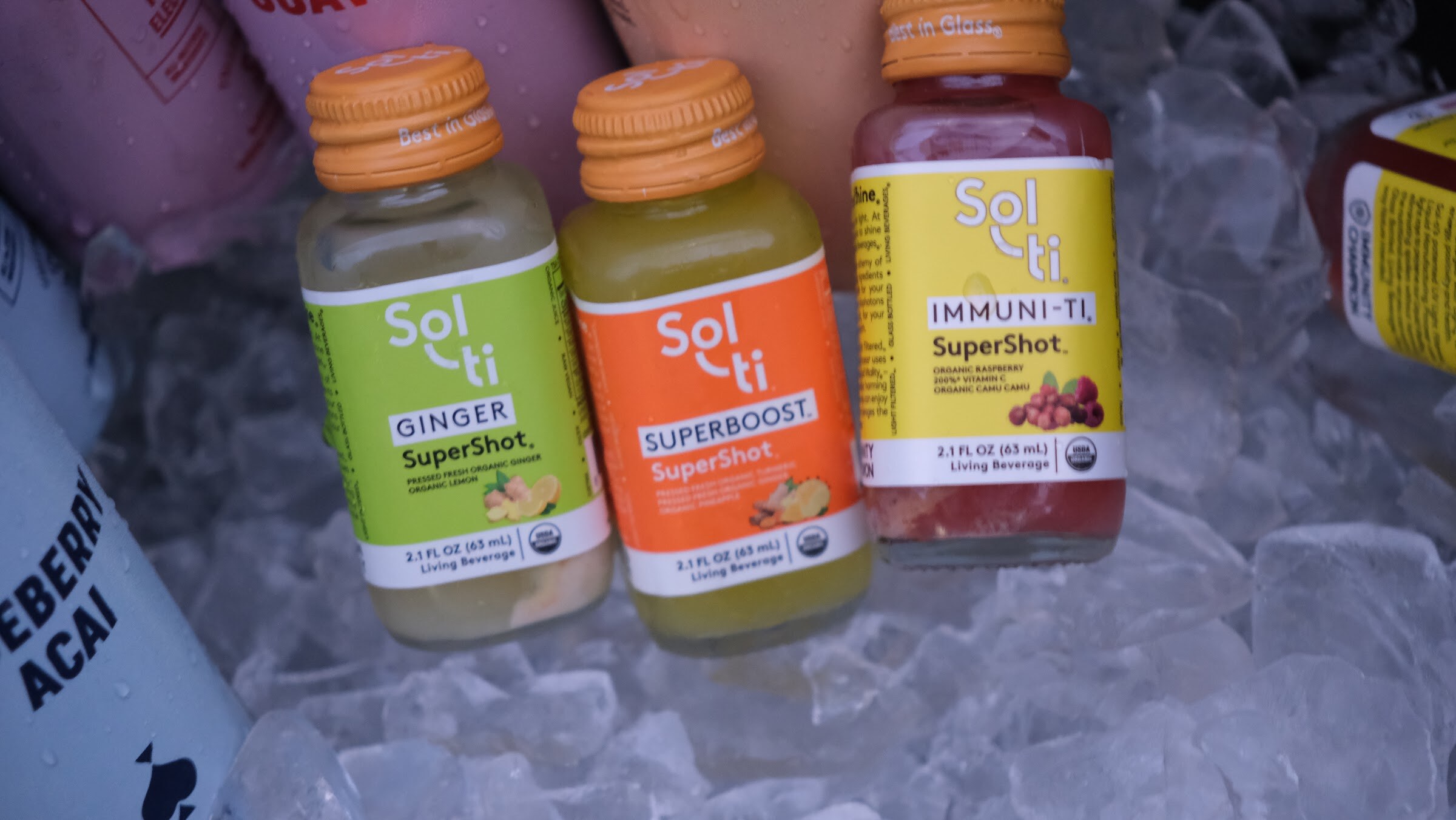Three small bottles labeled Sol-ti in ginger, superboost and immuni-tea flavors nestled in ice.