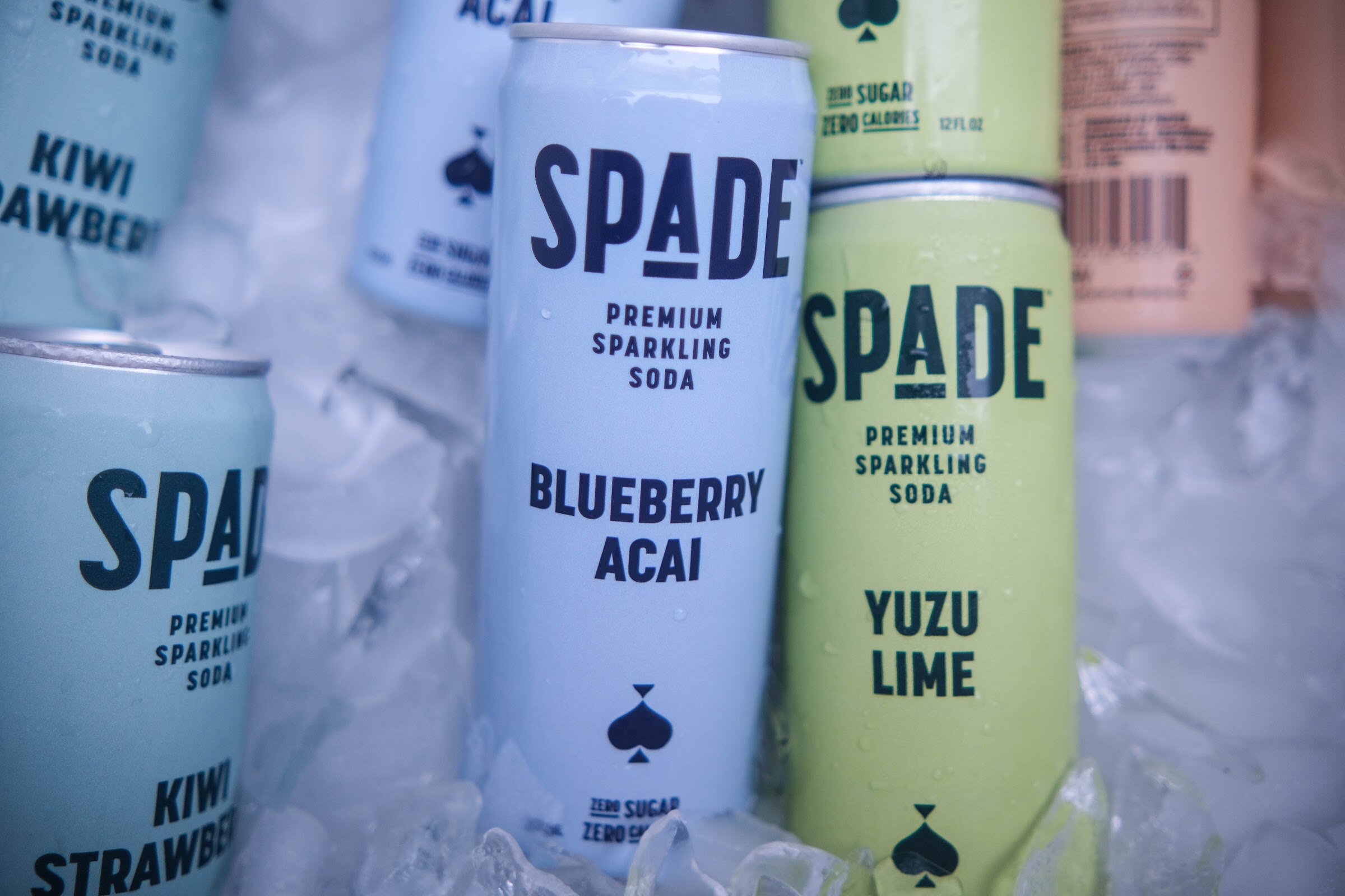 Close-up of Spade Blueberry Acai and Yuzu Lime sparkling soda cans in ice.