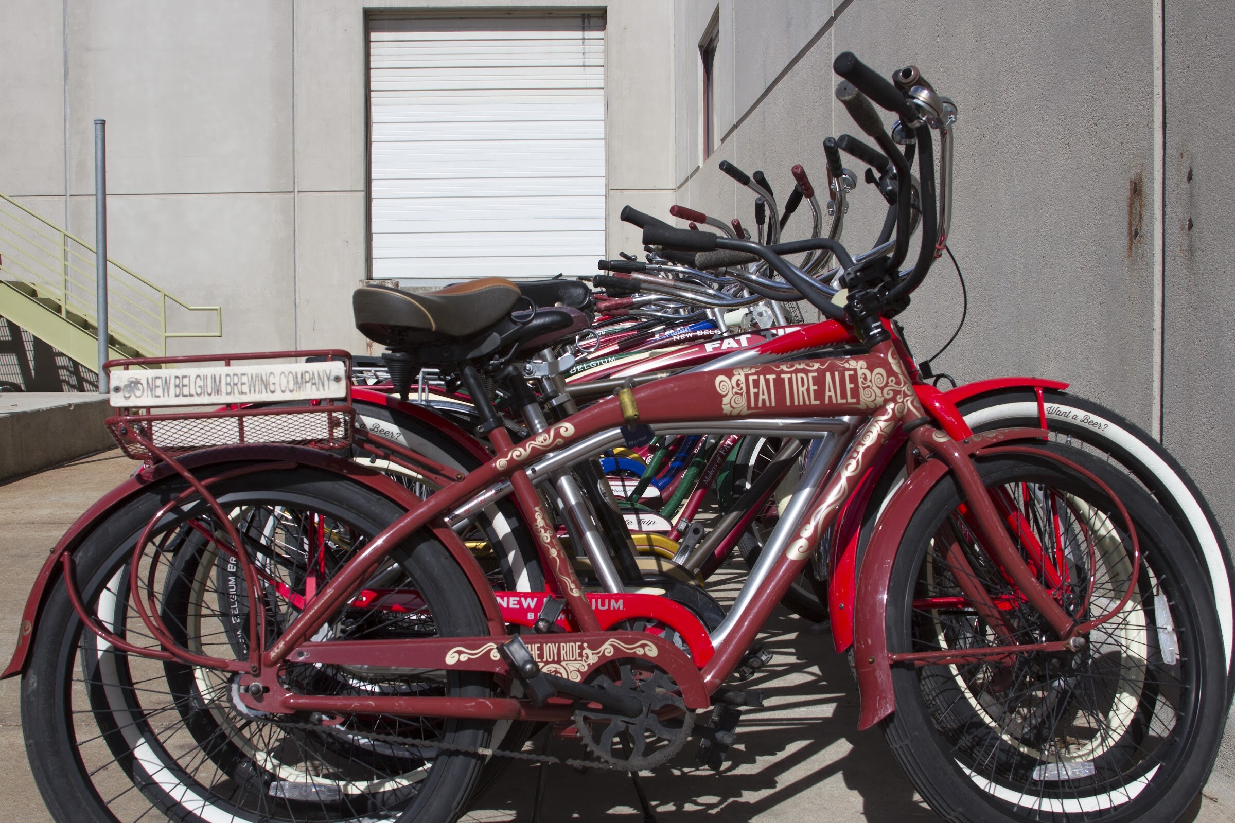 Cruiser bicycles stand in a row, with Fat Tire Ale and New Belgium markings on the nearest frames.