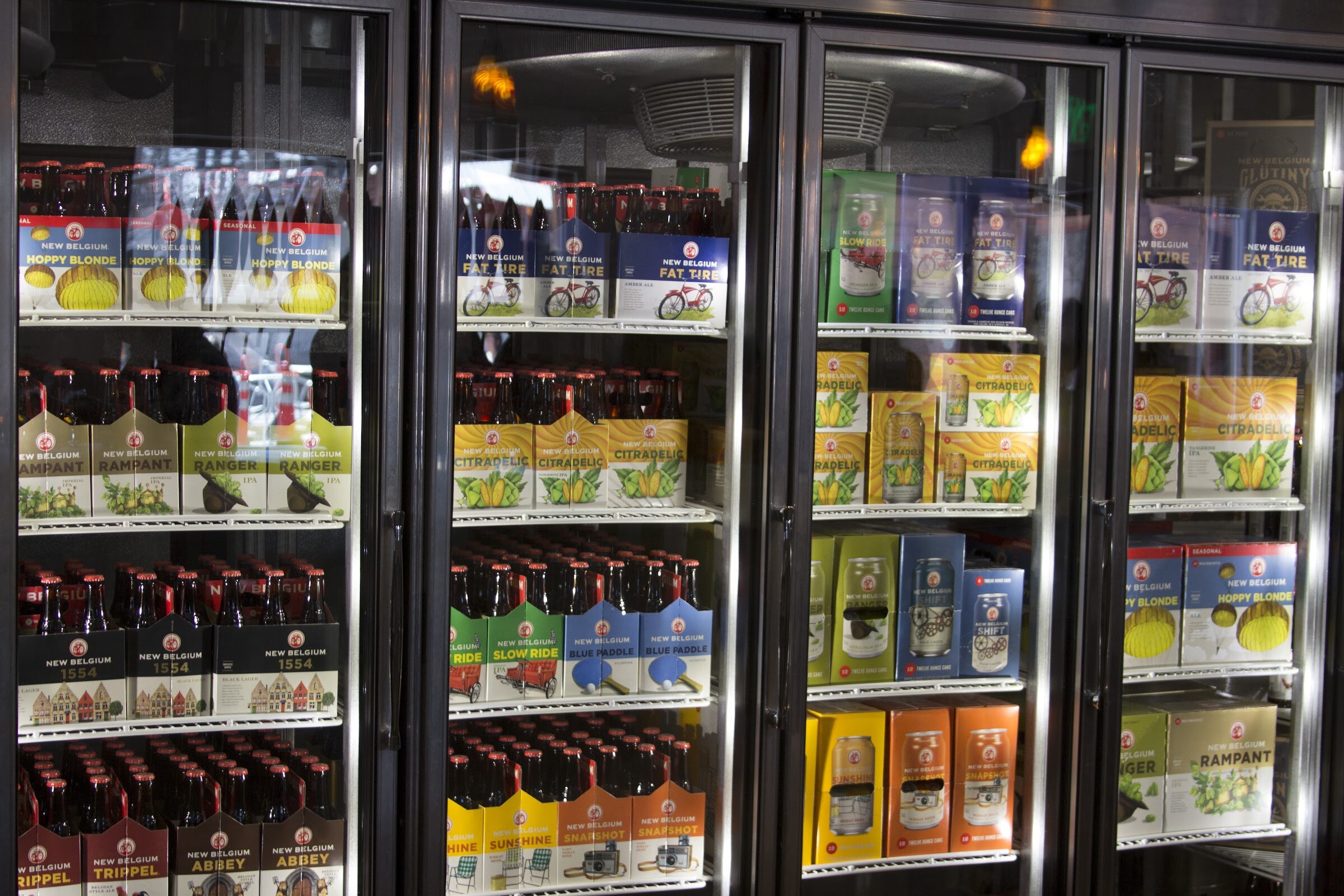 Glass-fronted refrigerators contain colorful packs of New Belgium beers including Fat Tire and Citradelic.