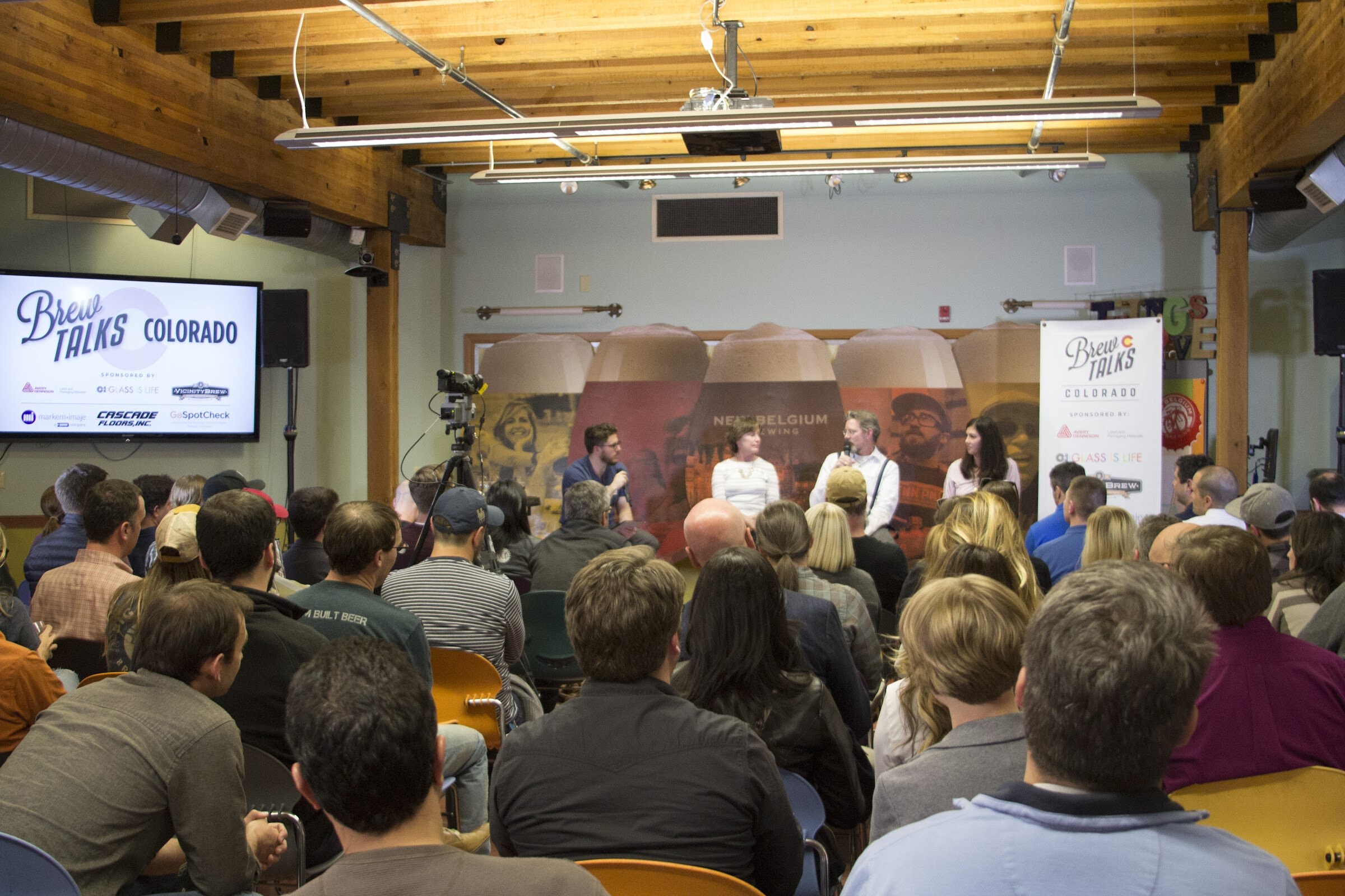 Rows of seated attendees face four panel participants between a Brew Talks screen and a matching banner.