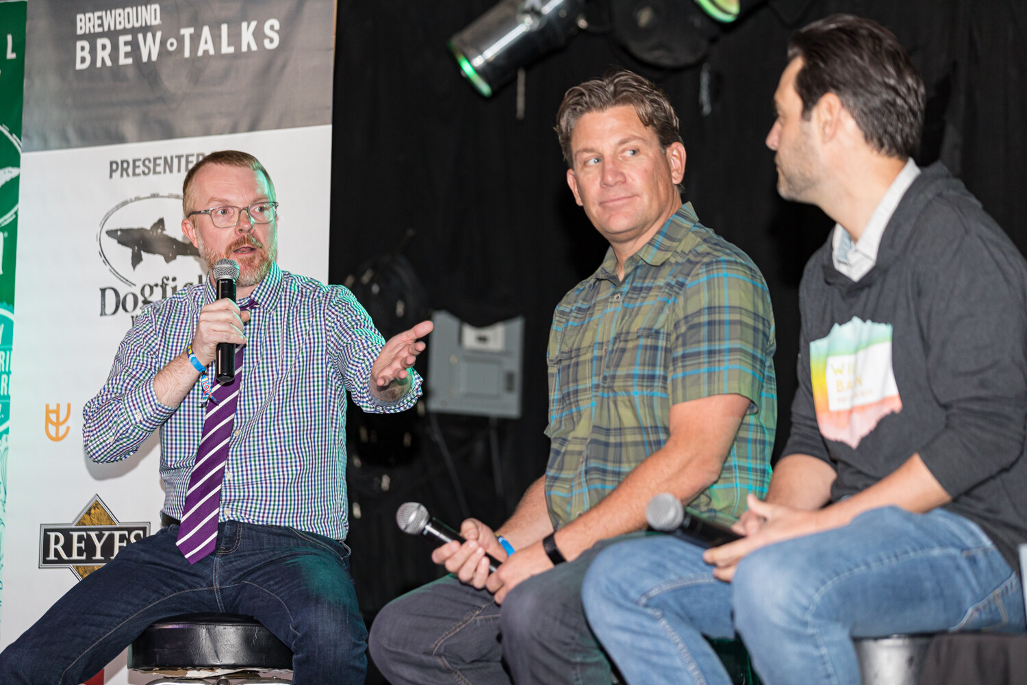 A moderator gesturing toward two seated panelists, with a Brewbound Brew Talks banner behind.
