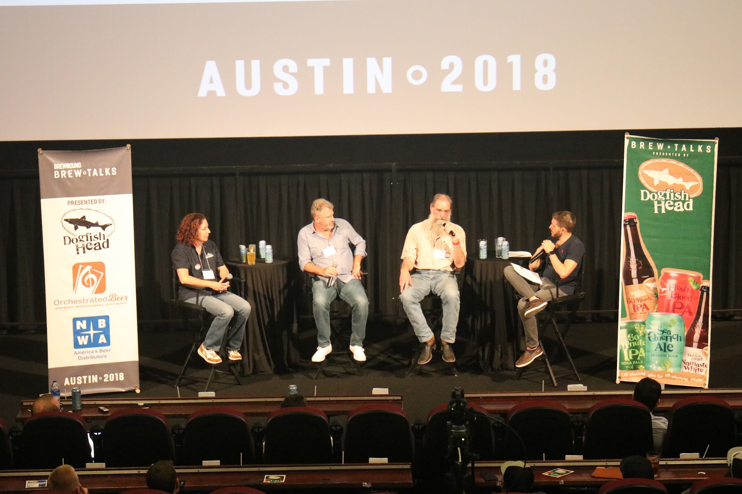 Four people seated on stools on a theater stage beneath a screen reading Austin 2018, with a Brew Talks banner at left and a Dogfish Head banner at right.