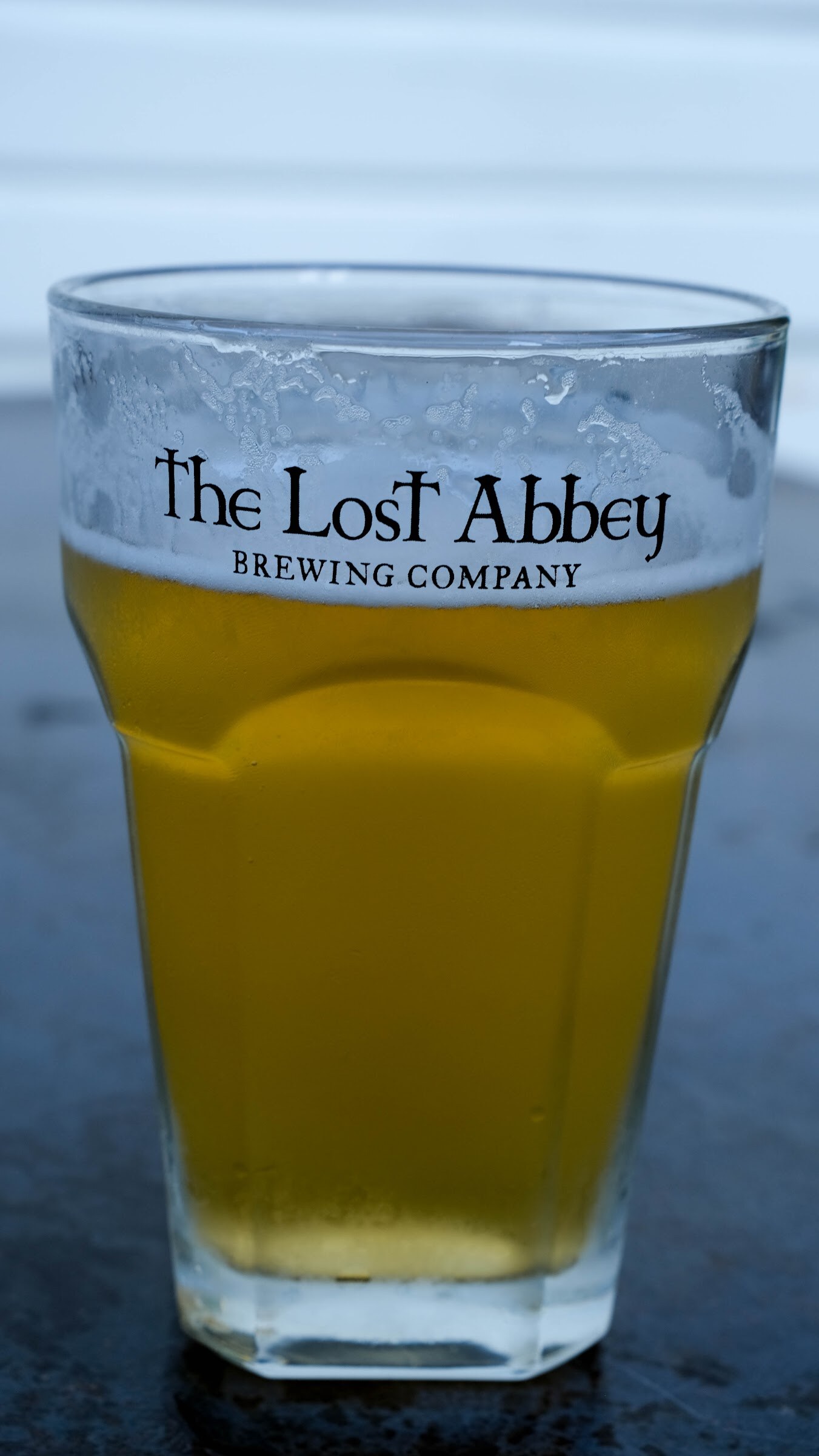 Pint glass of golden beer printed with The Lost Abbey Brewing Company logo.