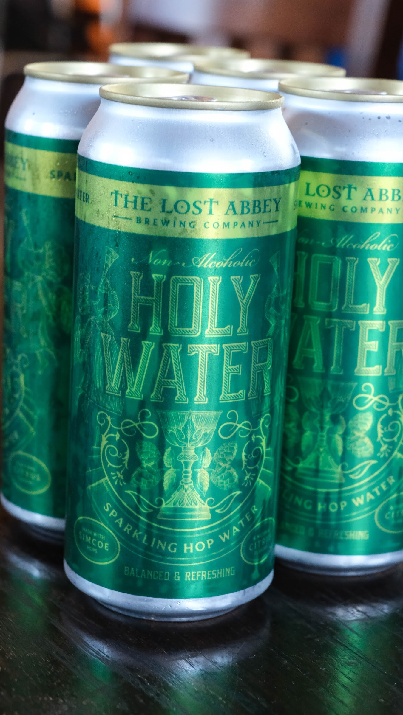 Four green cans labeled The Lost Abbey Holy Water non-alcoholic sparkling hop water.