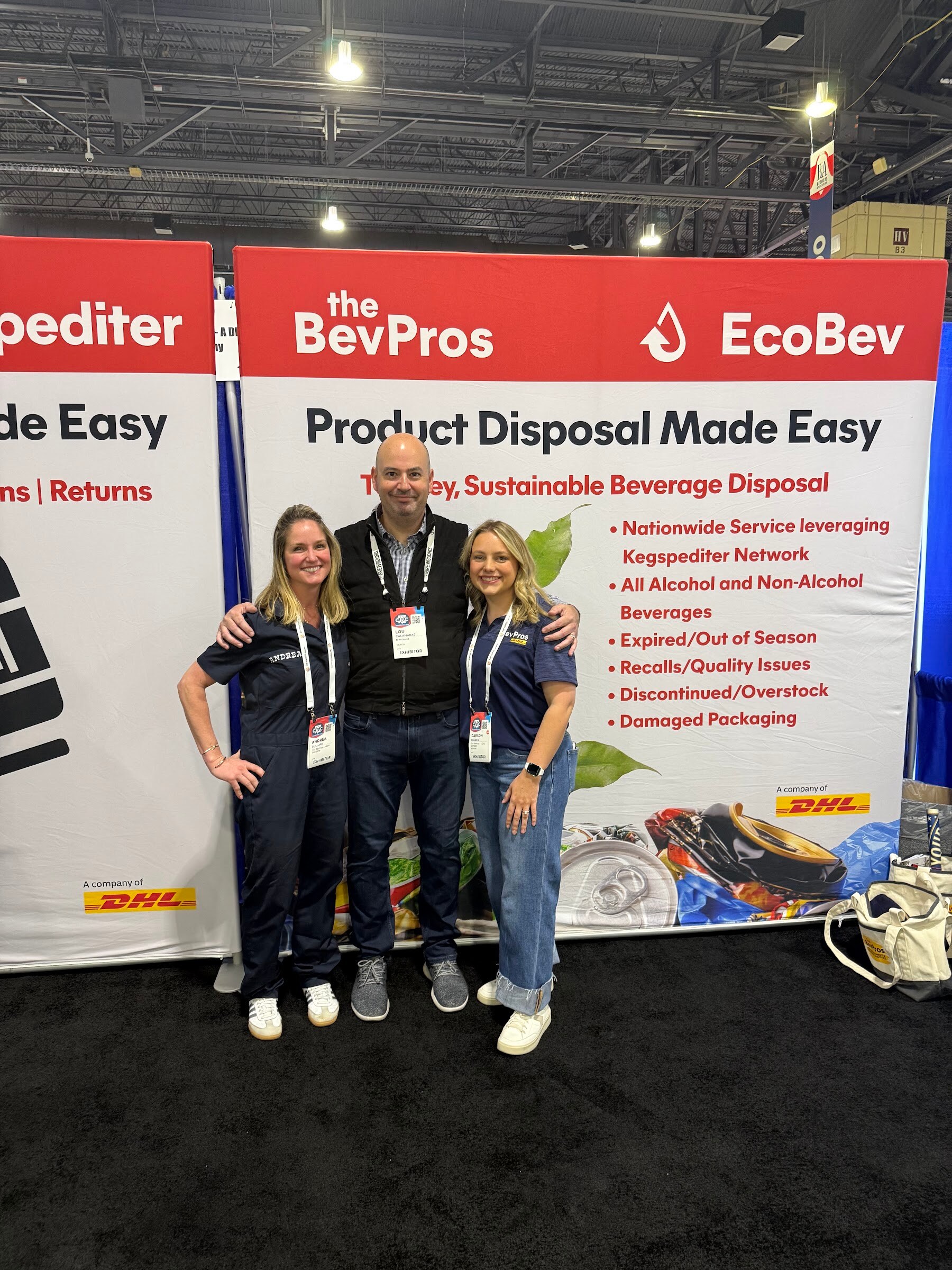 Three people pose in front of a red and white The BevPros and EcoBev banner reading Product Disposal Made Easy.