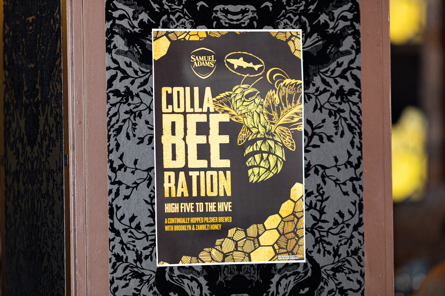 A black and gold poster reading CollaBEEration, High Five to the Hive, with the Samuel Adams and Dogfish Head logos.