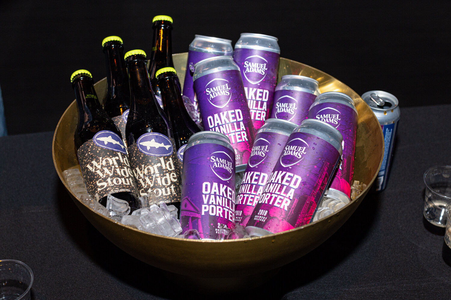 A gold bowl of ice with bottles labeled World Wide Stout and purple Samuel Adams Oaked Vanilla Porter cans.