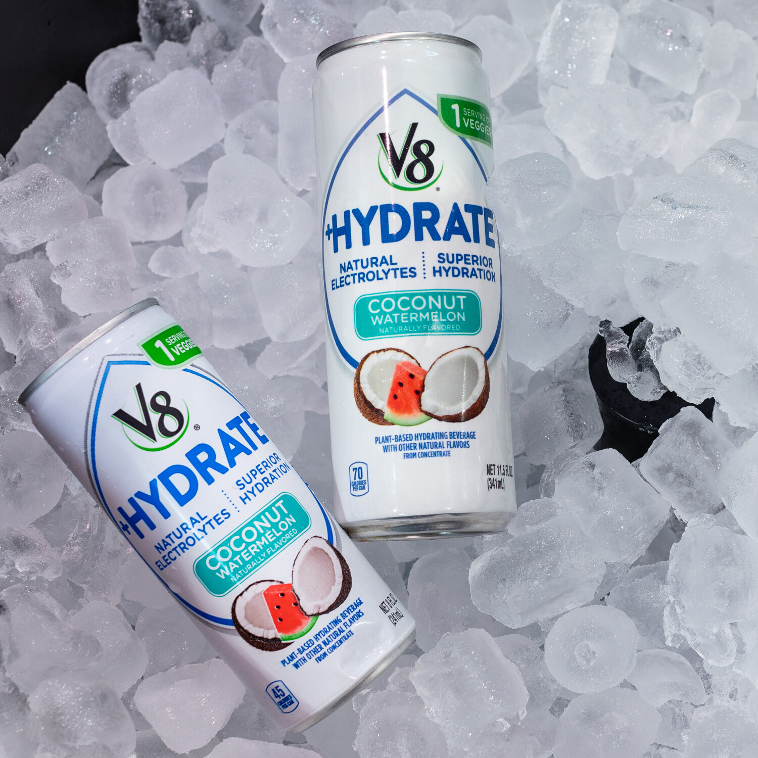 Two V8 Hydrate cans on crushed ice, one lying on its side.