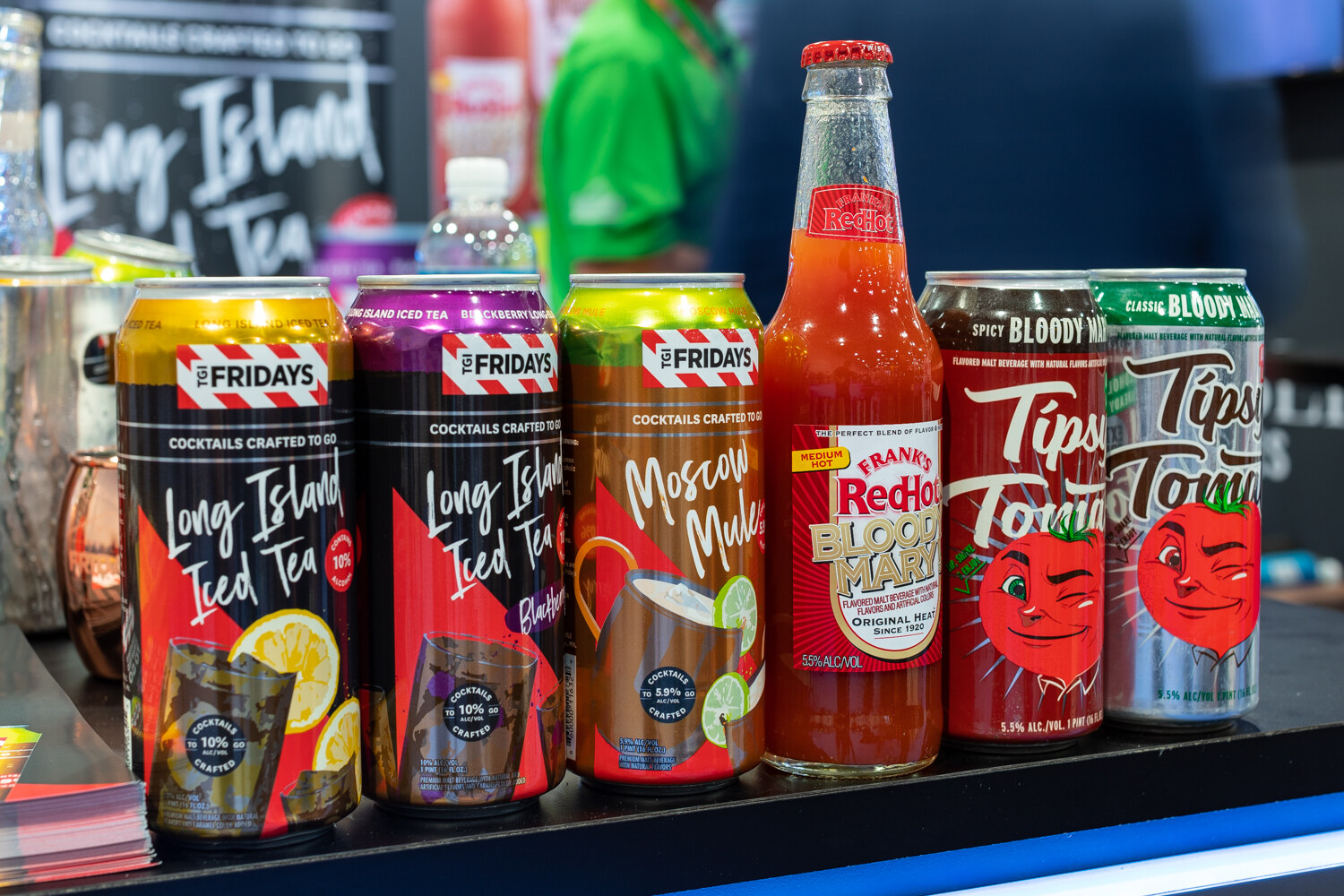 A shelf of colorful TGI Fridays cans and Tips Bloody Mary bottles.