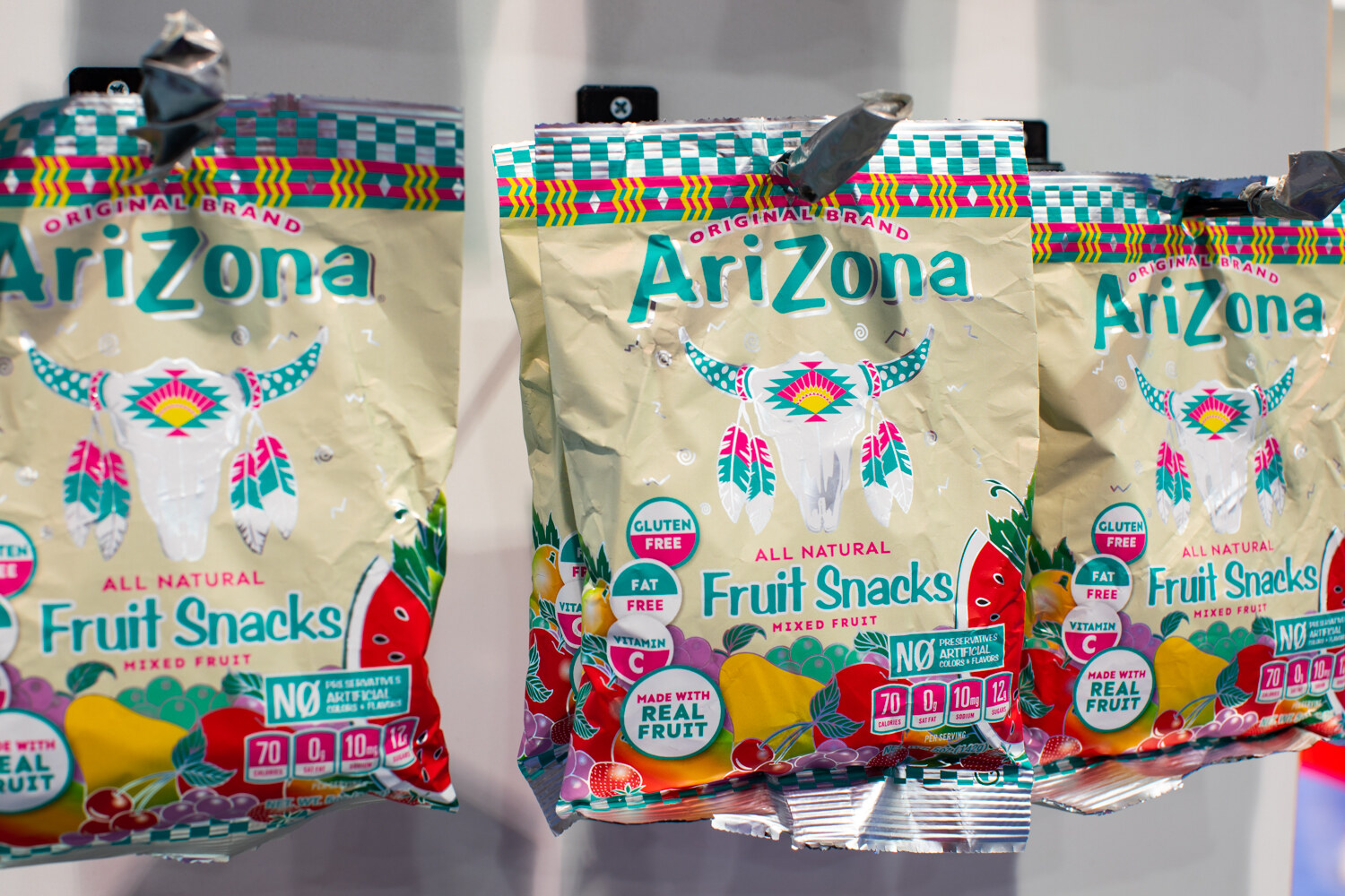 Several colorful Arizona fruit snack pouches hanging from clips.