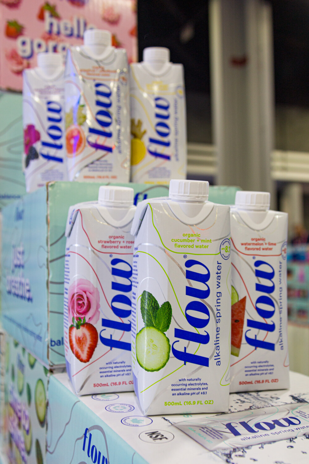 Several Flow cartons with fruit illustrations on a light blue stand.