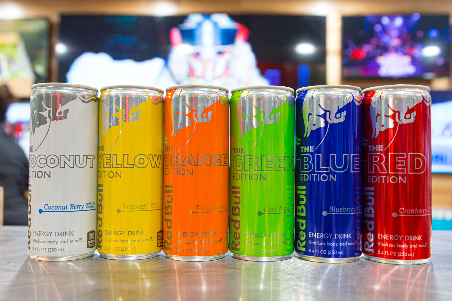 Red Bull cans in coconut, yellow, orange, green, blue and red editions in a row.