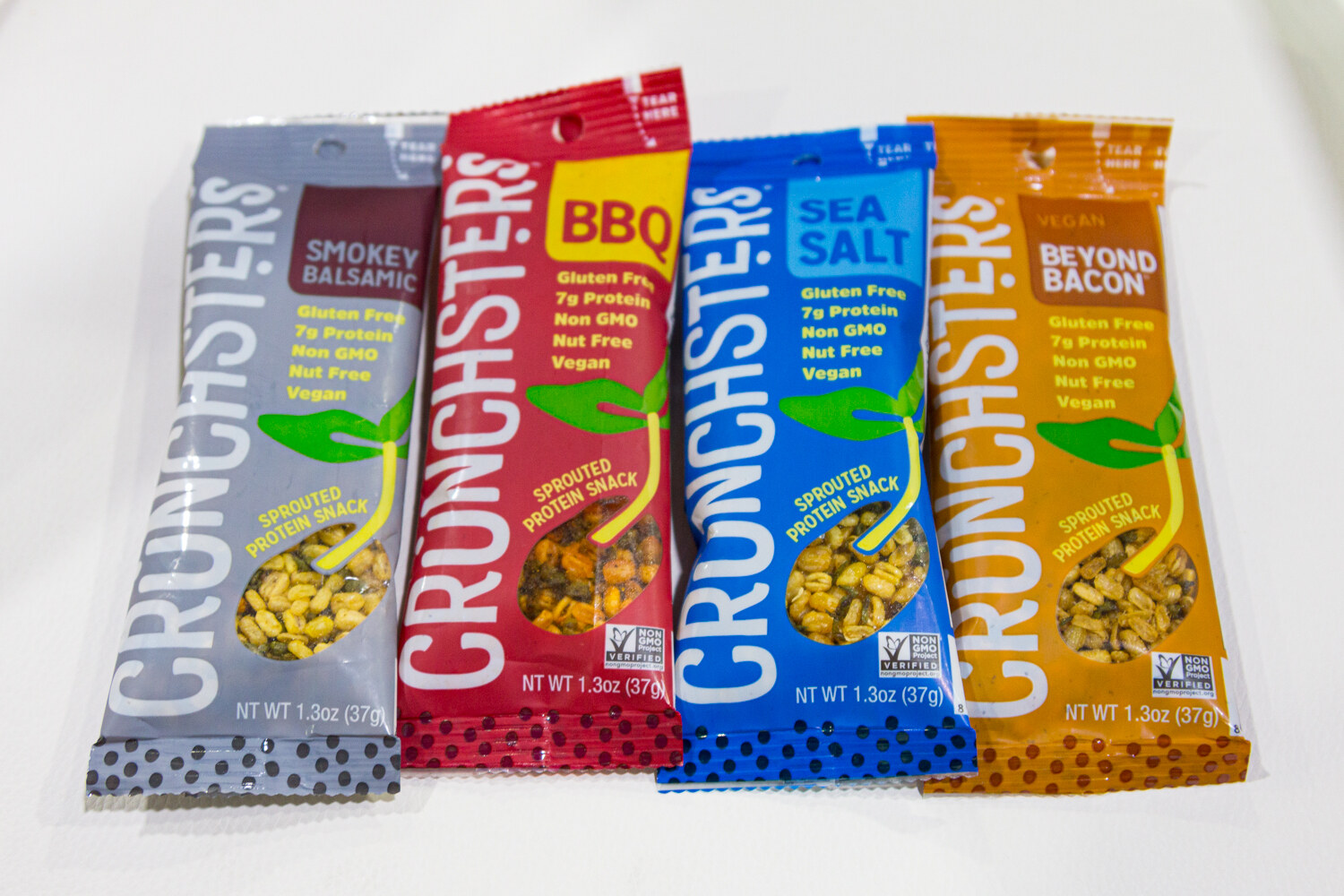 Crunchsters packets in Smokey Balsamic, BBQ, Sea Salt and Beyond Bacon flavors on a white surface.