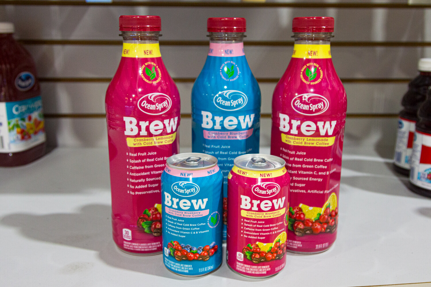 Three tall Ocean Spray Brew bottles with two smaller cans in front, in pink, blue and red.