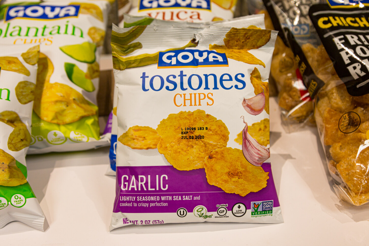 Goya Tostones Chips in garlic flavor on a counter with other chip bags around it.