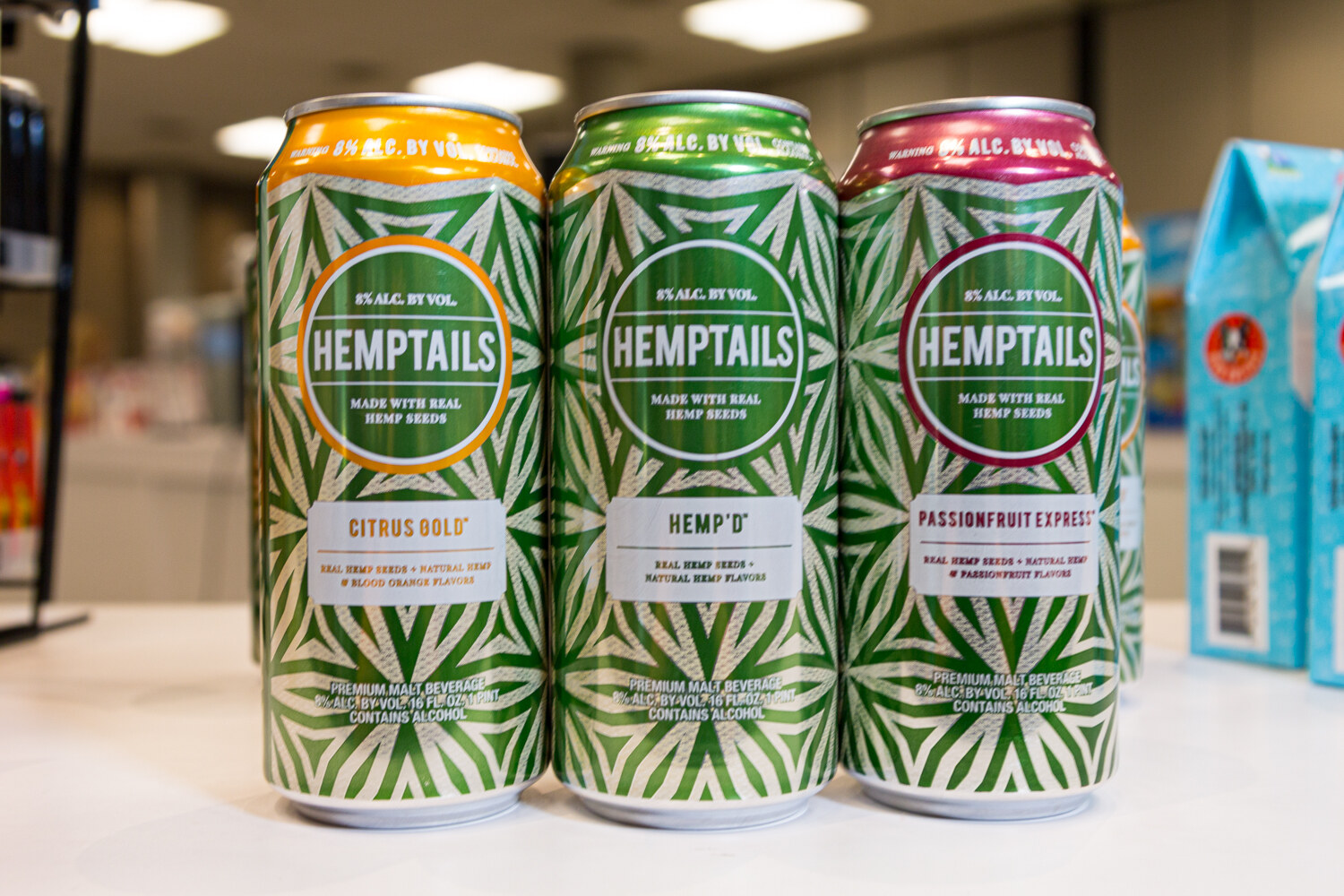 Three green-patterned Hemptails cans on a white counter.