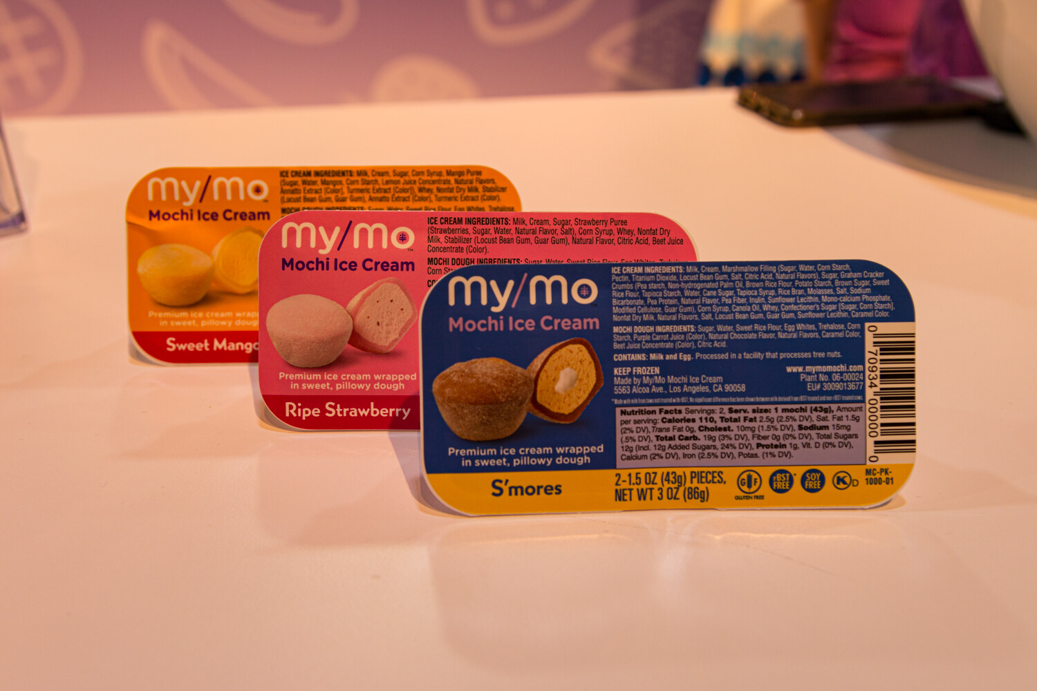 Orange, pink and blue my/mo Mochi Ice Cream cups in sweet mango, ripe strawberry and s'mores.
