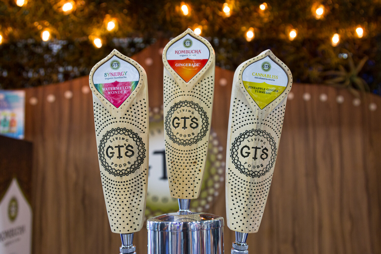 Three cream-colored GT's tap handles with kombucha flavors and a chrome tap base.