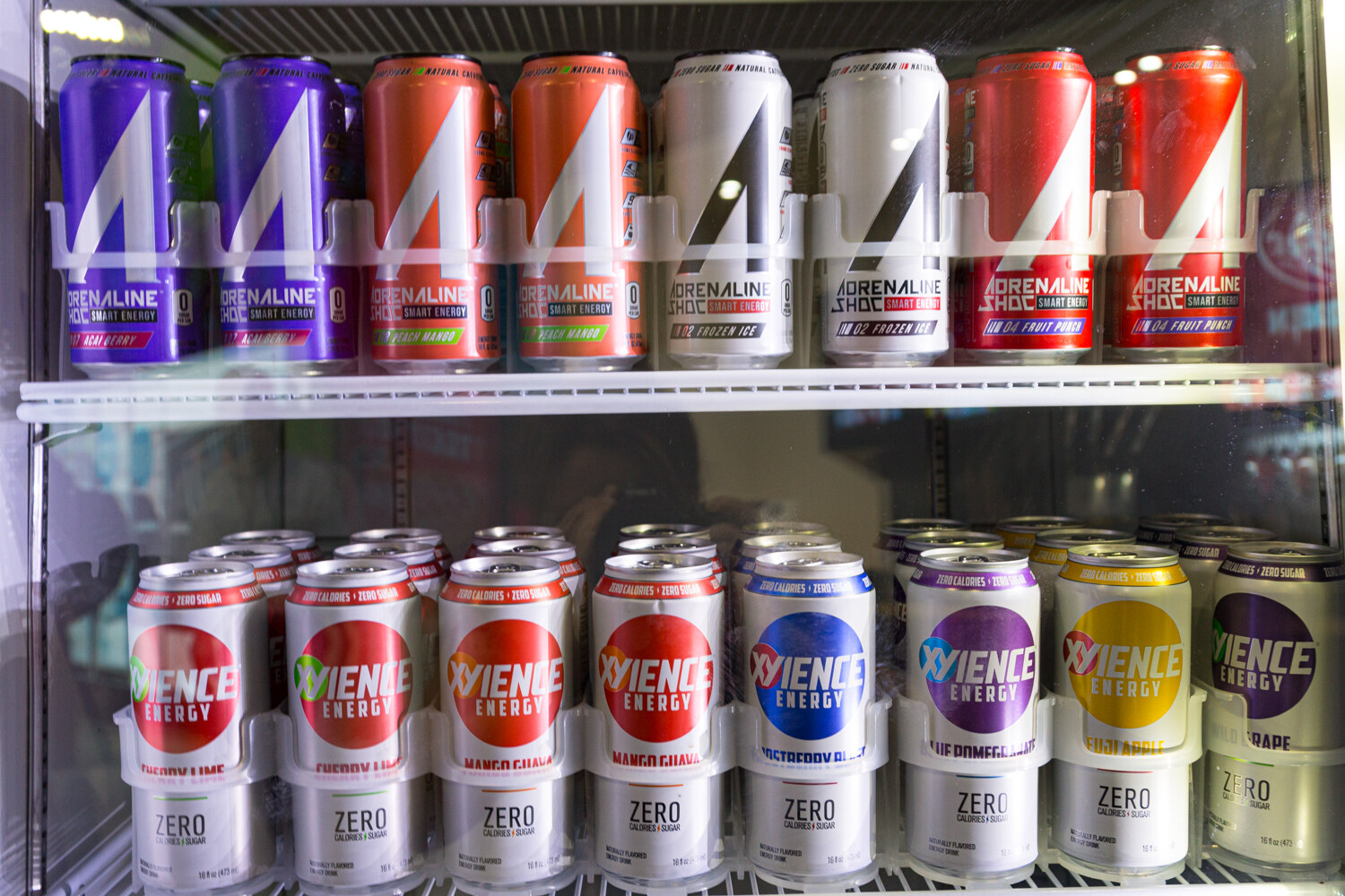 A glass-door cooler stocked with Adrenaline Shoc cans above Xyience Energy cans.