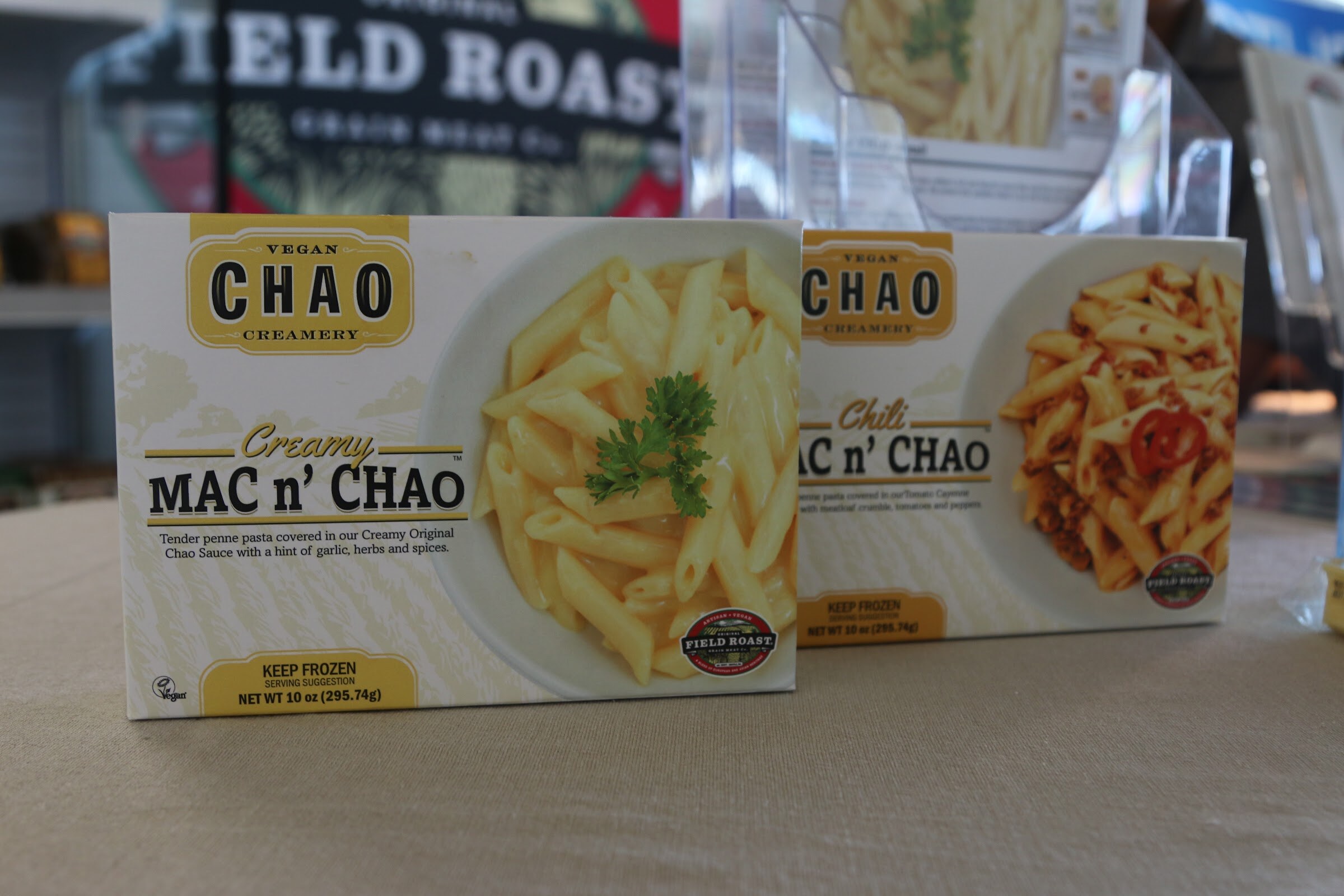 Two frozen Chao Creamery mac and cheese boxes on a round table, with a Field Roast banner and a clear display behind.