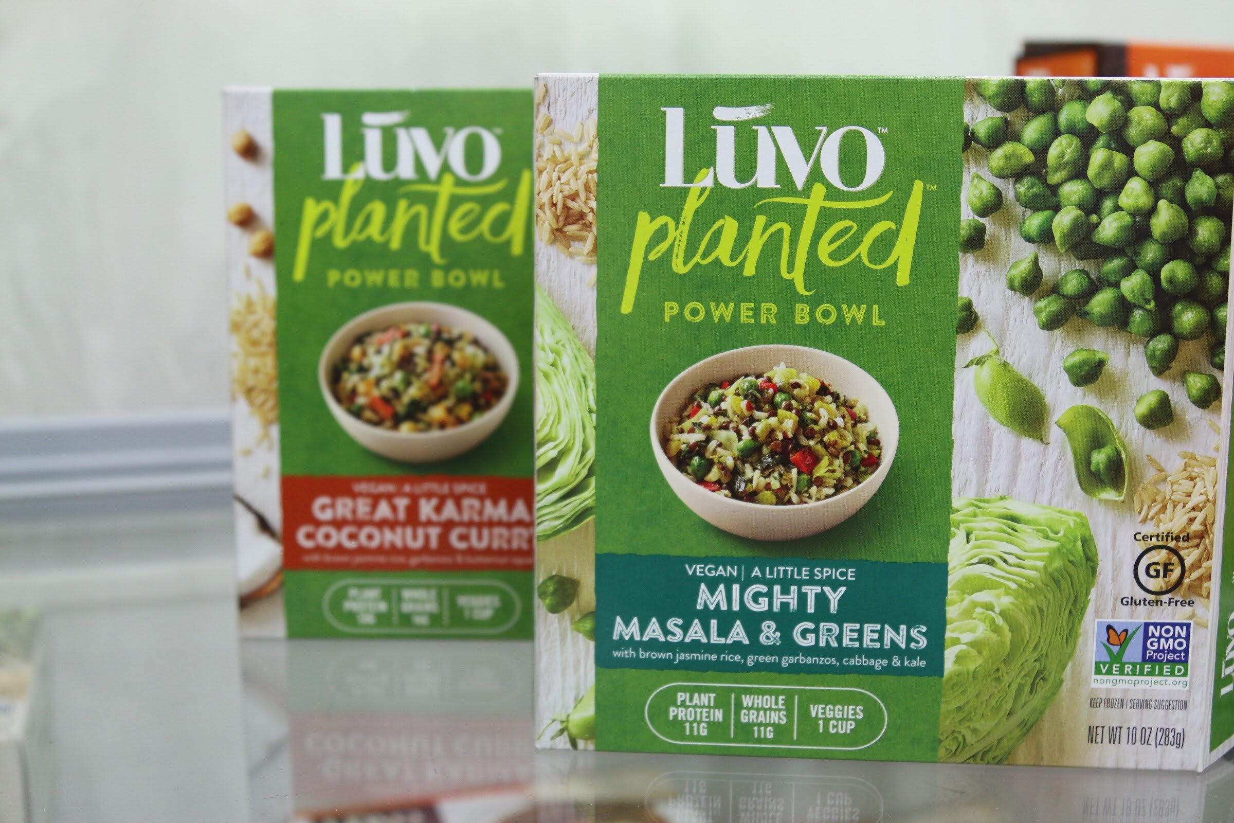 Two green Luvo Planted Power Bowl boxes showing a bowl of grains and vegetables beside photos of cabbage and peas.