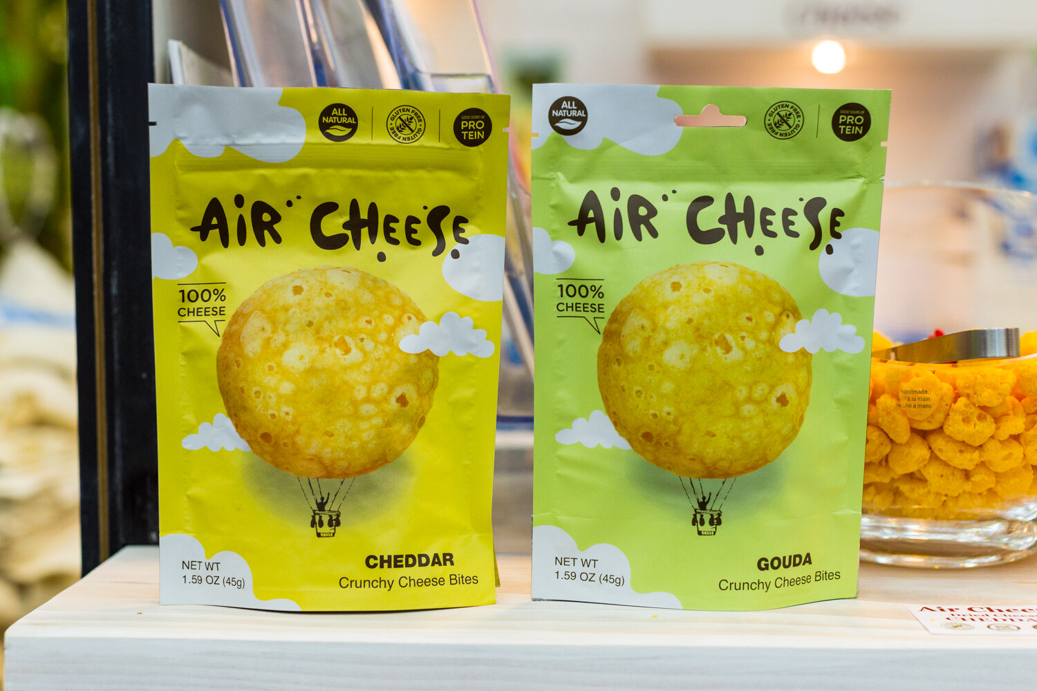 Two bags of Air Cheese, one yellow cheddar and one green gouda, each with a hot air balloon illustration.