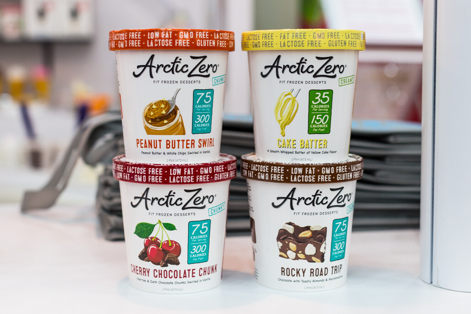 Four stacked Arctic Zero pints, Peanut Butter Swirl, Cake Batter, Cherry Chocolate Chunk and Rocky Road Trip.