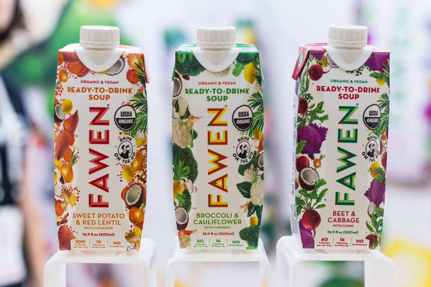 Three colorful Fawen soup cartons with vegetable illustrations on small clear stands in front of a blurred background.