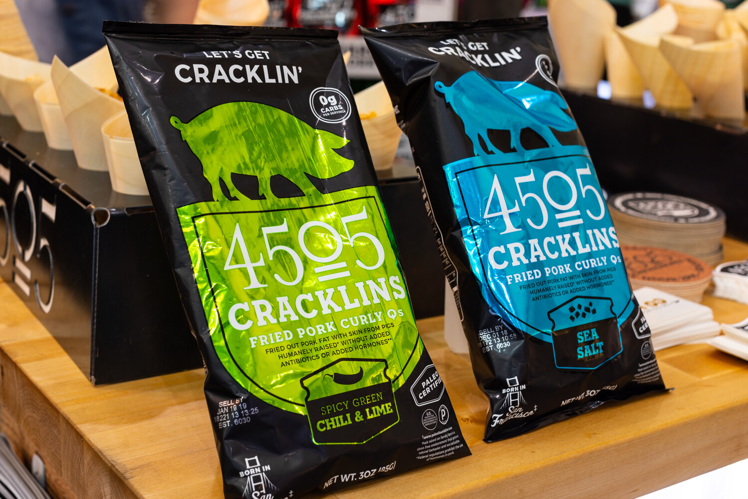 Two metallic green and blue 4505 Cracklins bags on a butcher-block counter.