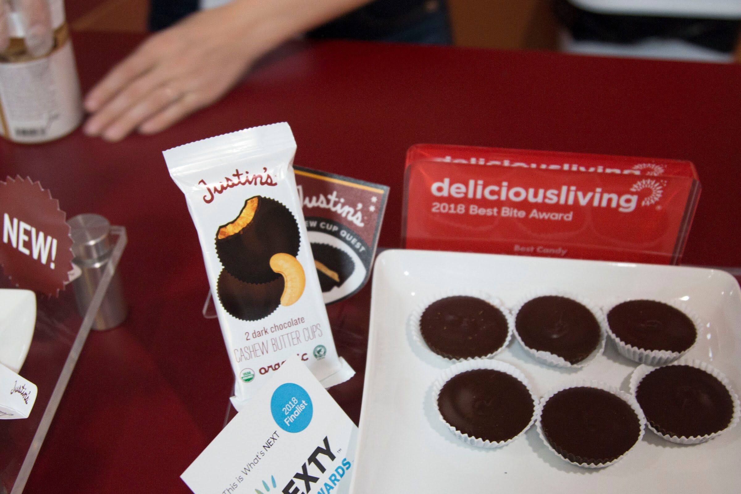 A Justin's package and a plate of chocolate cups next to a red award plaque and a NEXTY Awards card.