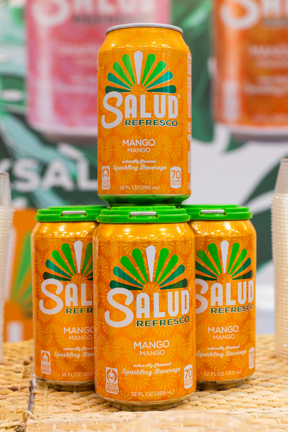 A stack of orange Salud Refresco Mango cans with a single can balanced on top.