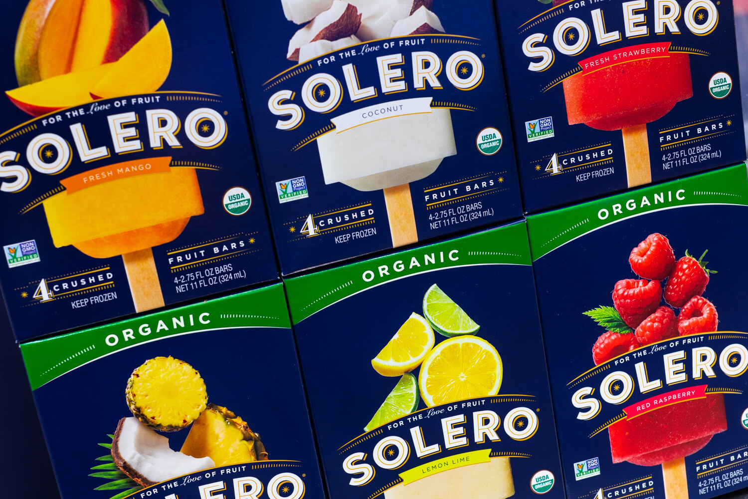 Stacked navy Solero boxes showing fruit bars with mango, coconut and raspberry photography.