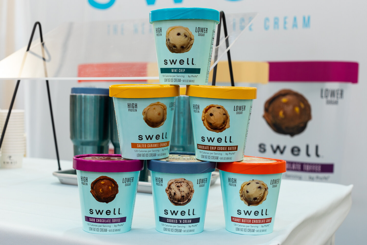 A pyramid of teal Swell ice cream pints on a white-covered table.