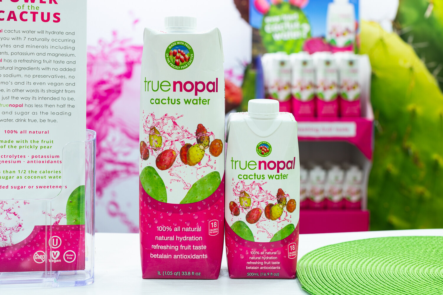 Two True Nopal cartons in pink and white on a table in front of a cactus-themed backdrop.