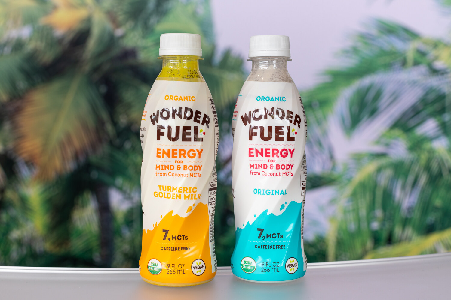 Two white plastic Wonder Fuel bottles with yellow and blue wave graphics against a blurred palm-tree backdrop.