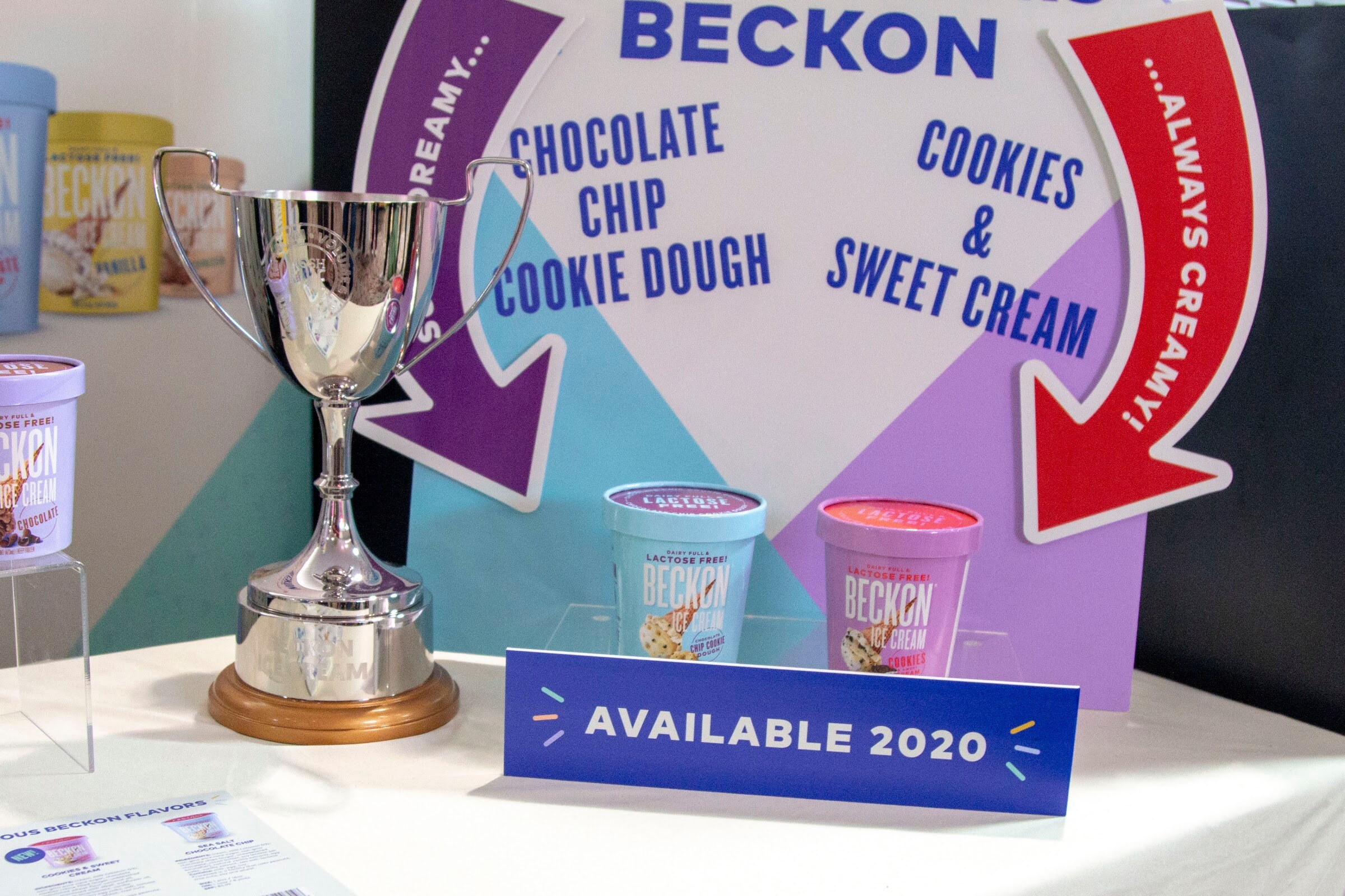 Beckon ice cream pints beside a silver cup and a blue Available 2020 sign.