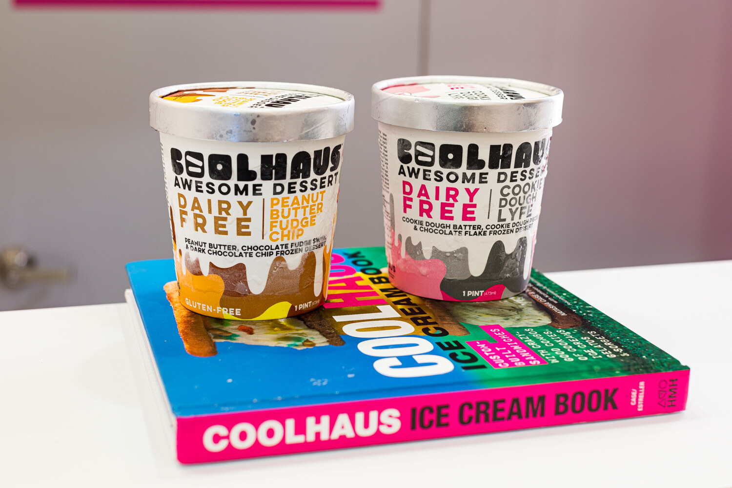 Two Coolhaus pints on a pink, blue and green Coolhaus Ice Cream Book.