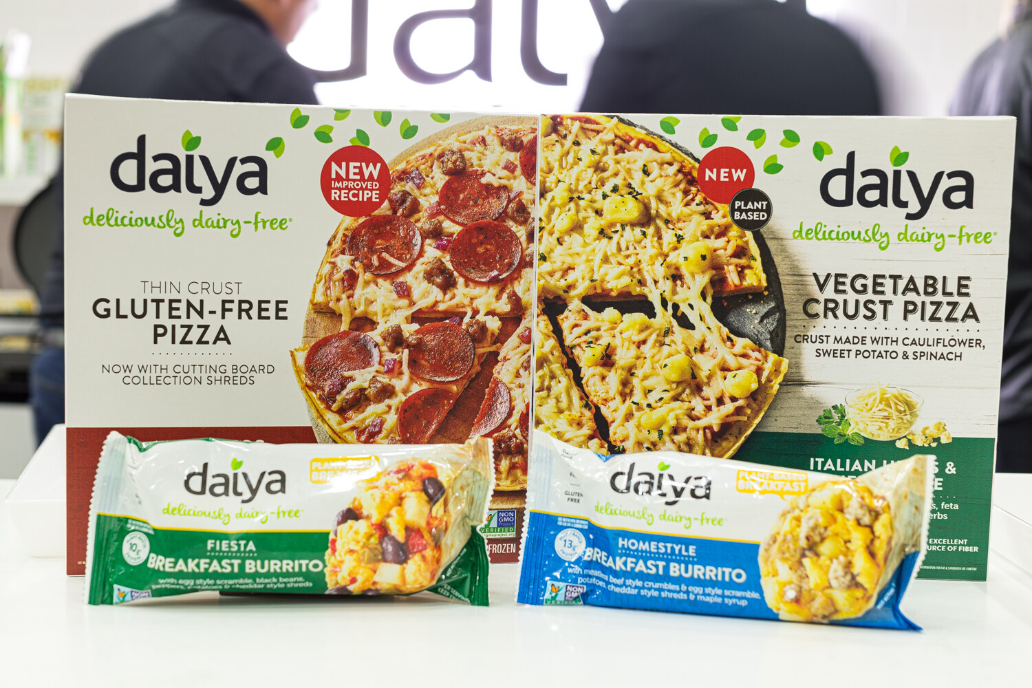 Daiya gluten-free pizza and vegetable crust pizza boxes with two breakfast burritos in front.