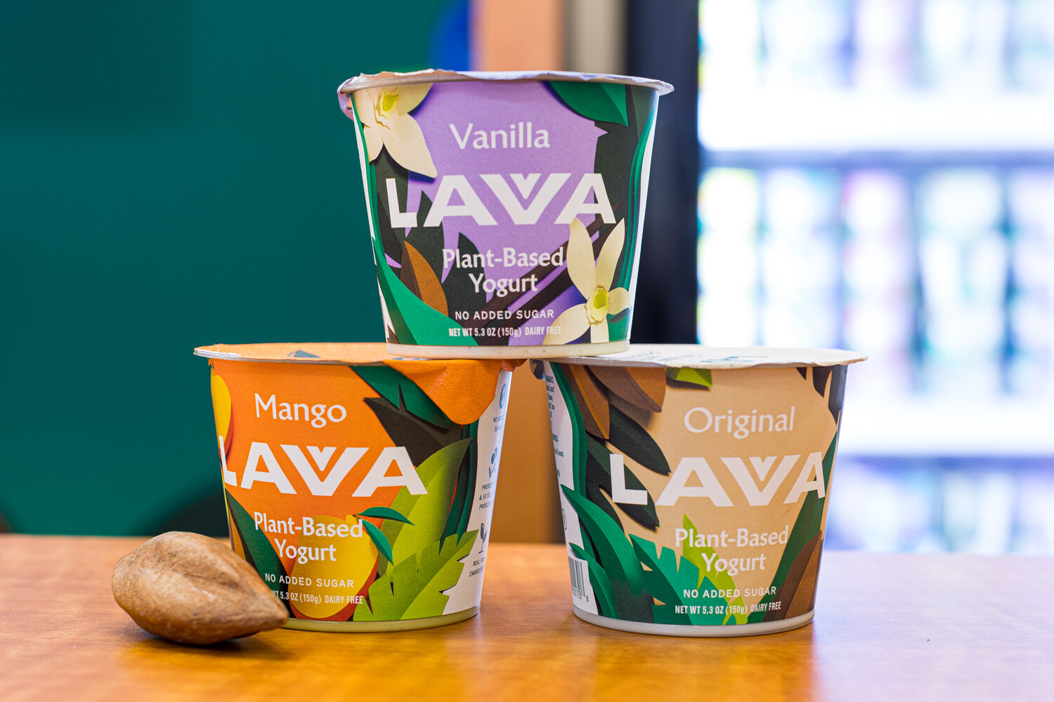 Cups of Lavva Vanilla, Mango and Original plant-based yogurt on a wooden table.