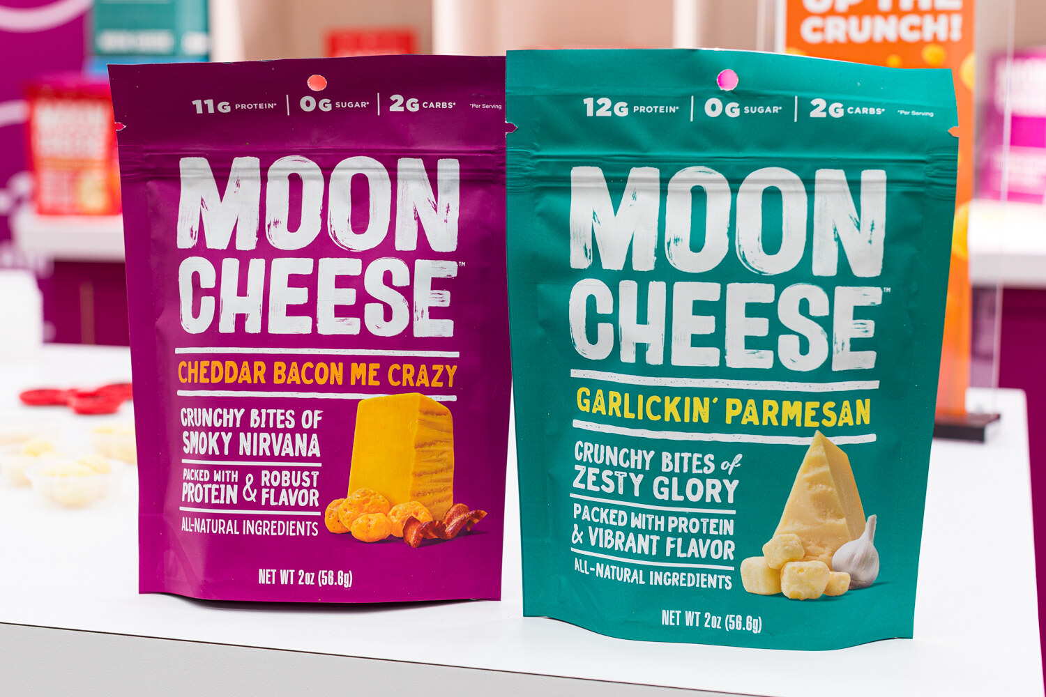 Two Moon Cheese bags, one magenta and one teal, on a white counter.