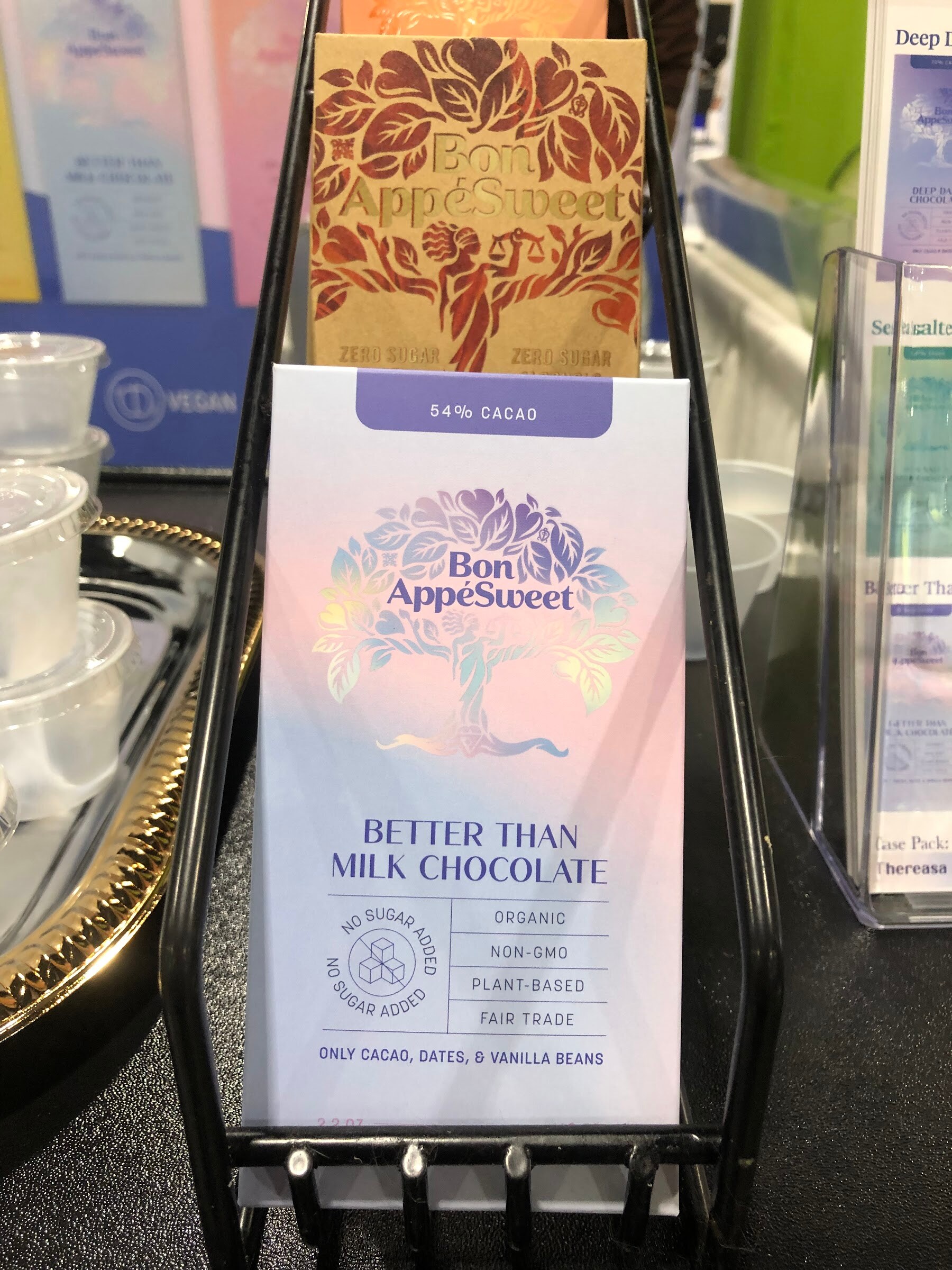 Bon AppeSweet better than milk chocolate bar in a black wire stand with a gold bar behind it
