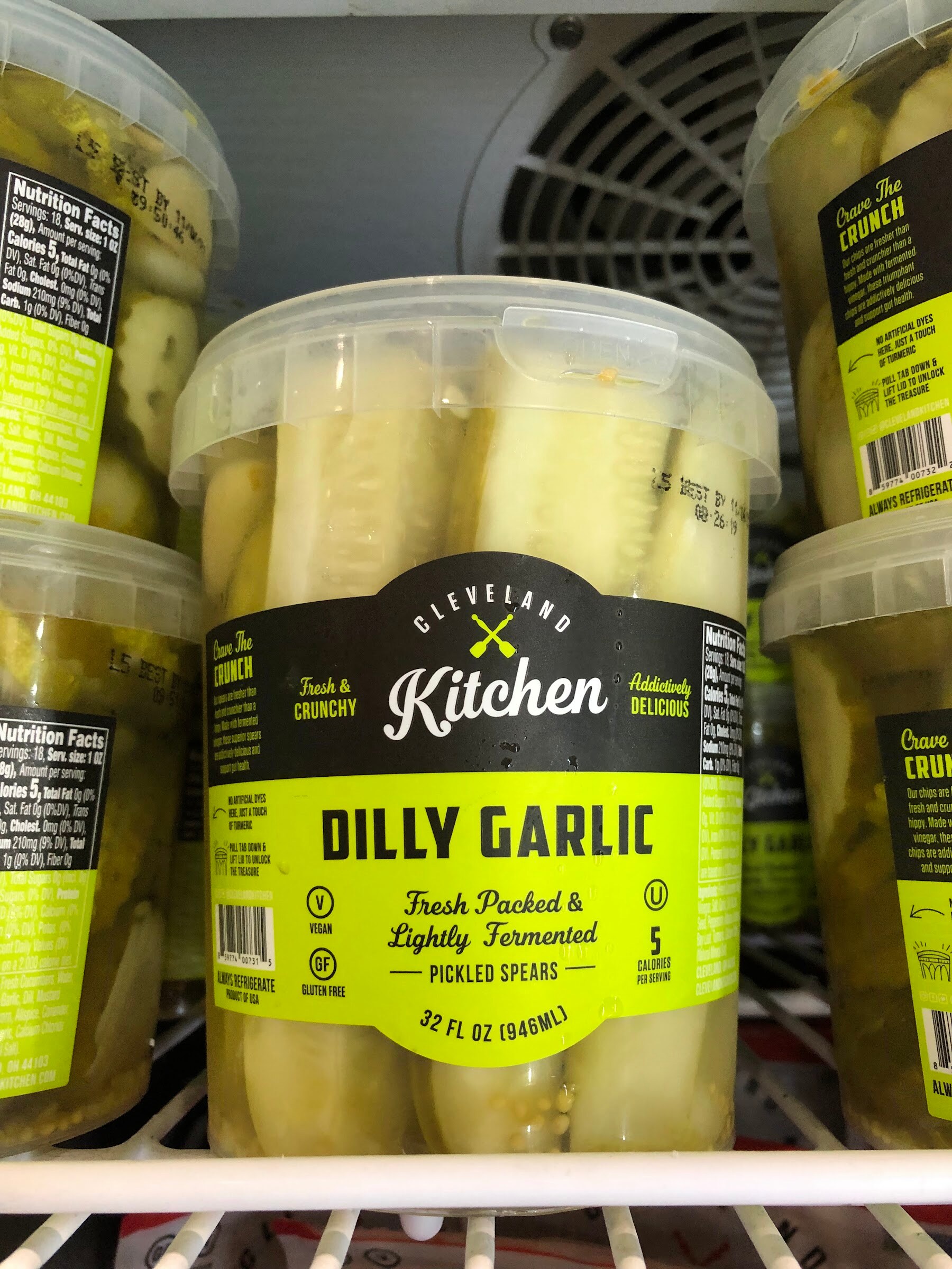 Tubs of Cleveland Kitchen Dilly Garlic fresh packed pickled spears in a refrigerated case
