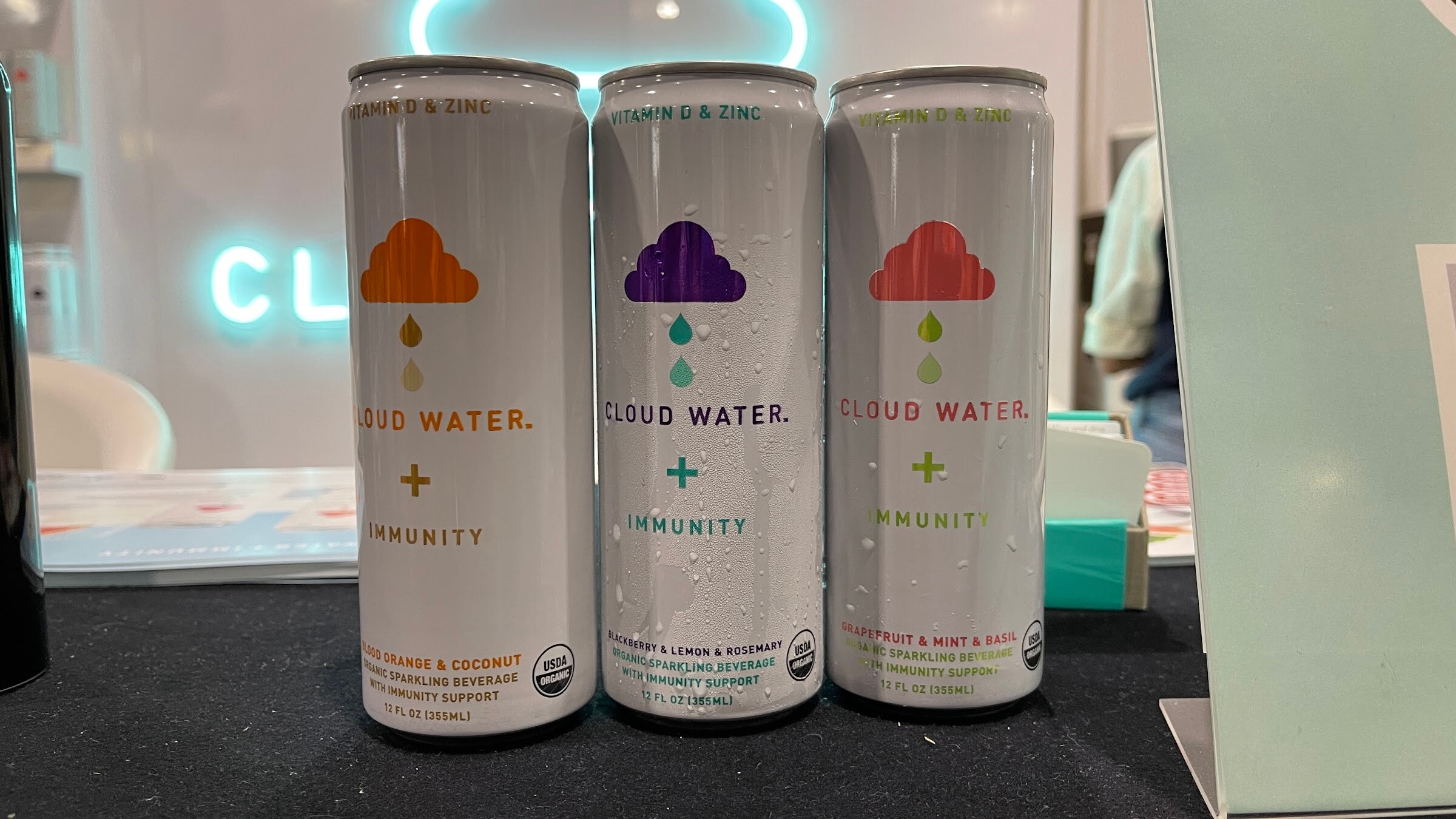 Three Cloud Water Immunity cans with cloud logos on a black table