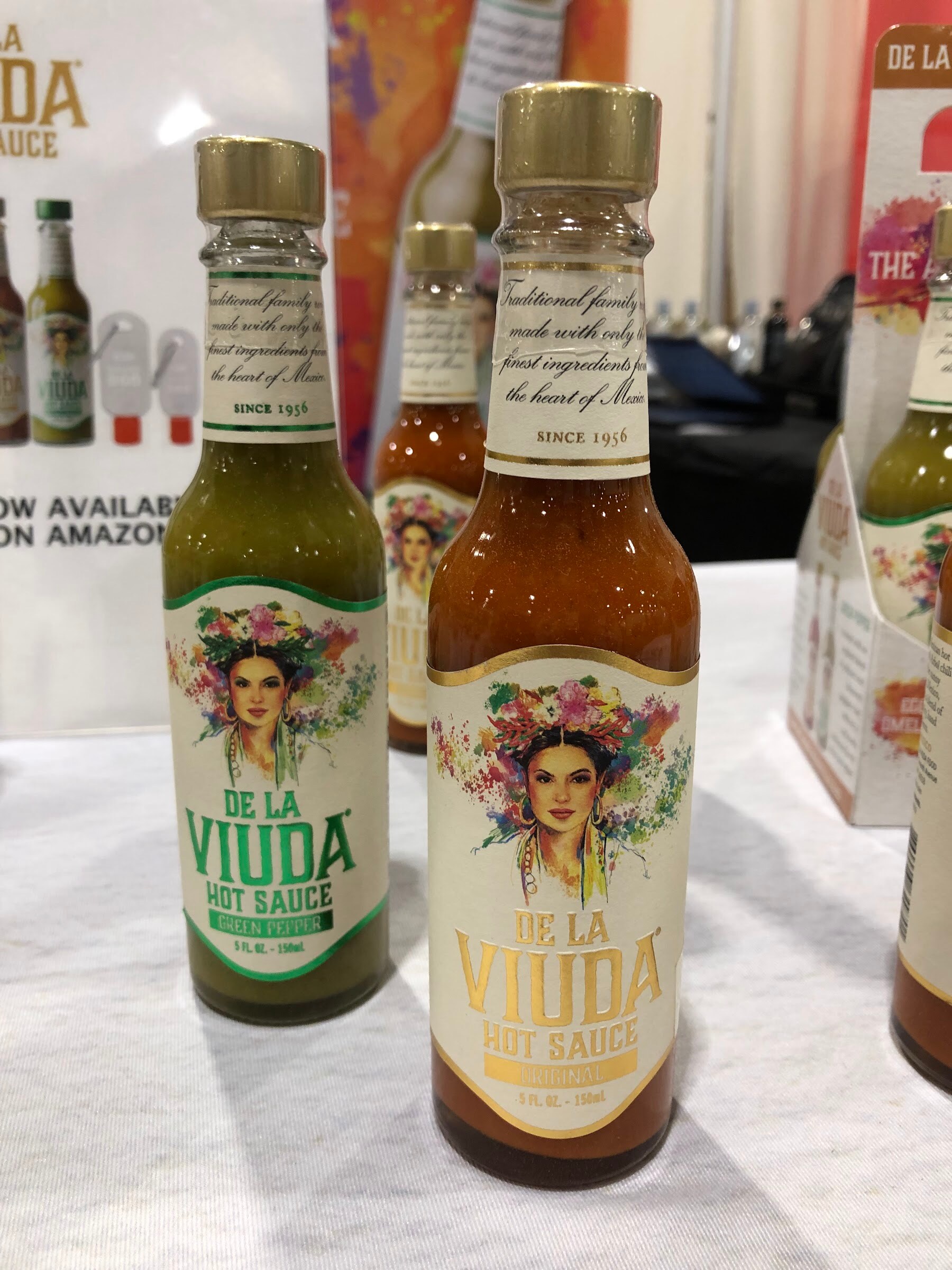 Bottles of De La Viuda hot sauce with a woman and flowers on the label on a white tablecloth