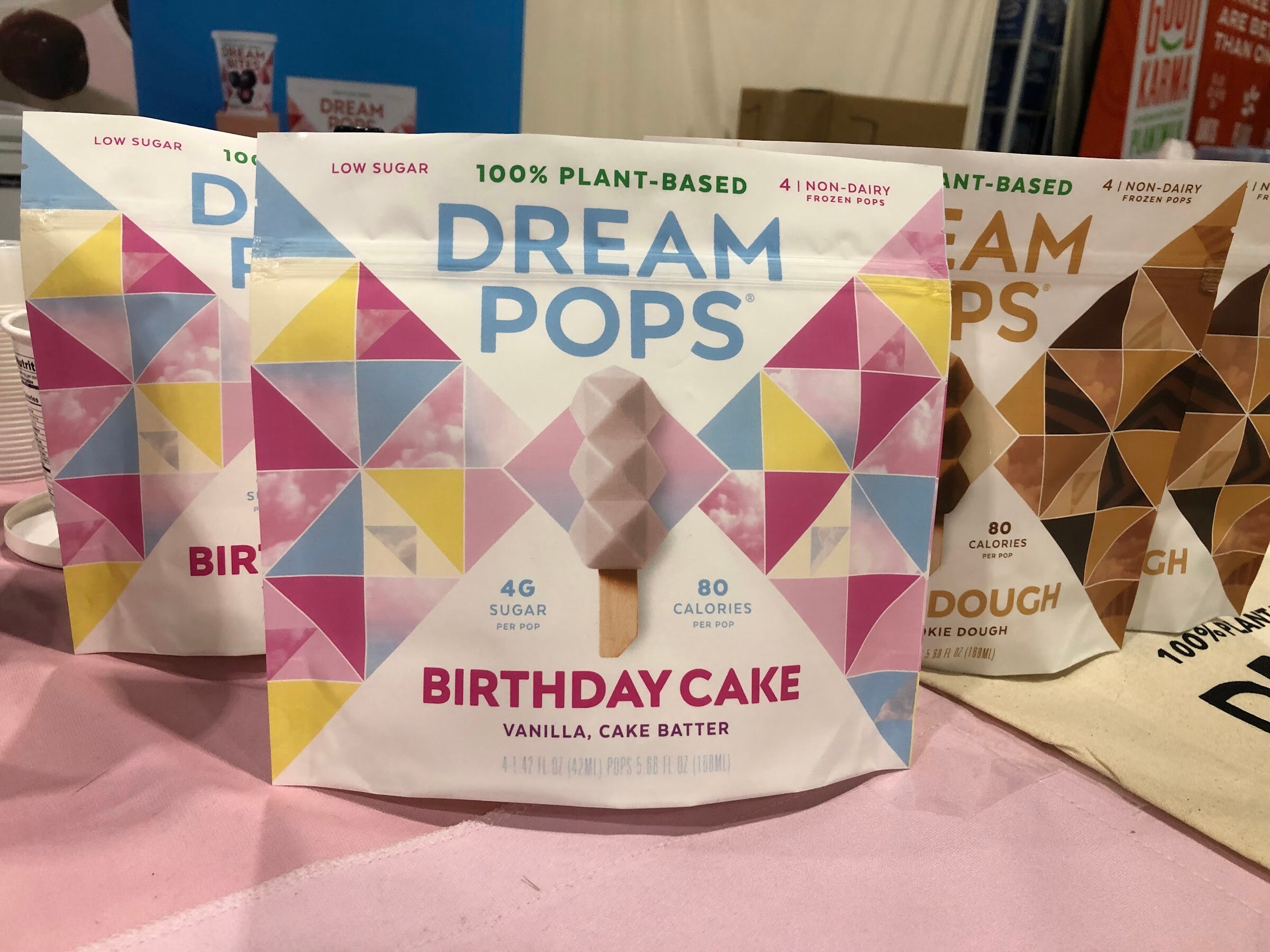 Dream Pops plant-based frozen dessert bags in birthday cake and cookie dough flavors on a pink tablecloth